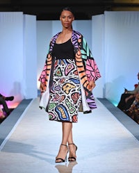 a model walks the runway wearing a colorful skirt and jacket